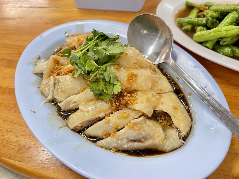 ไก่เบตงสับวางบนจานกระเบื้อง ราดซีอิ๊ว โรยกระเทียมเจียวและผักชี