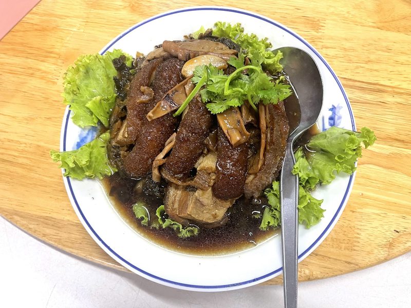 เคาหยกหมูสามชั้นกับผักกาดดองในน้ำเคาหยกสีเข้ม วางบนใบผักกาด