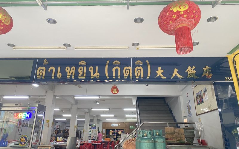 หน้าร้านต้าเหยิน ป้ายสีกรมท่าตัวอักษรทองเขียนว่า ต้าเหยิน (กิตติ) 大人飯店 ใต้โคมแดง มองเห็นห้องอาหารชั้นล่าง